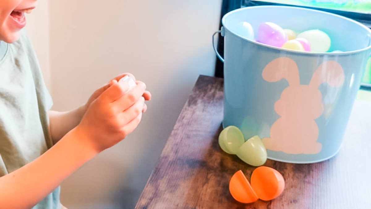 kid opening plastic easter egg with printable easter egg messages inside