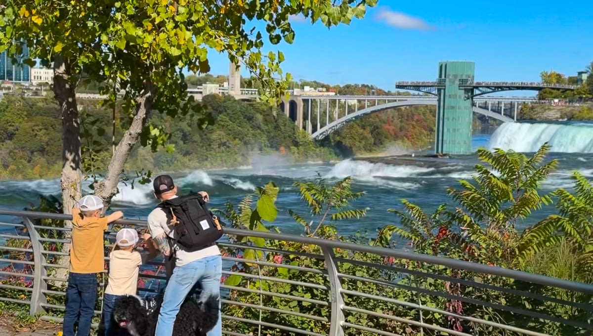Family visiting Niagara Falls looks out at the falls from Goat Island.